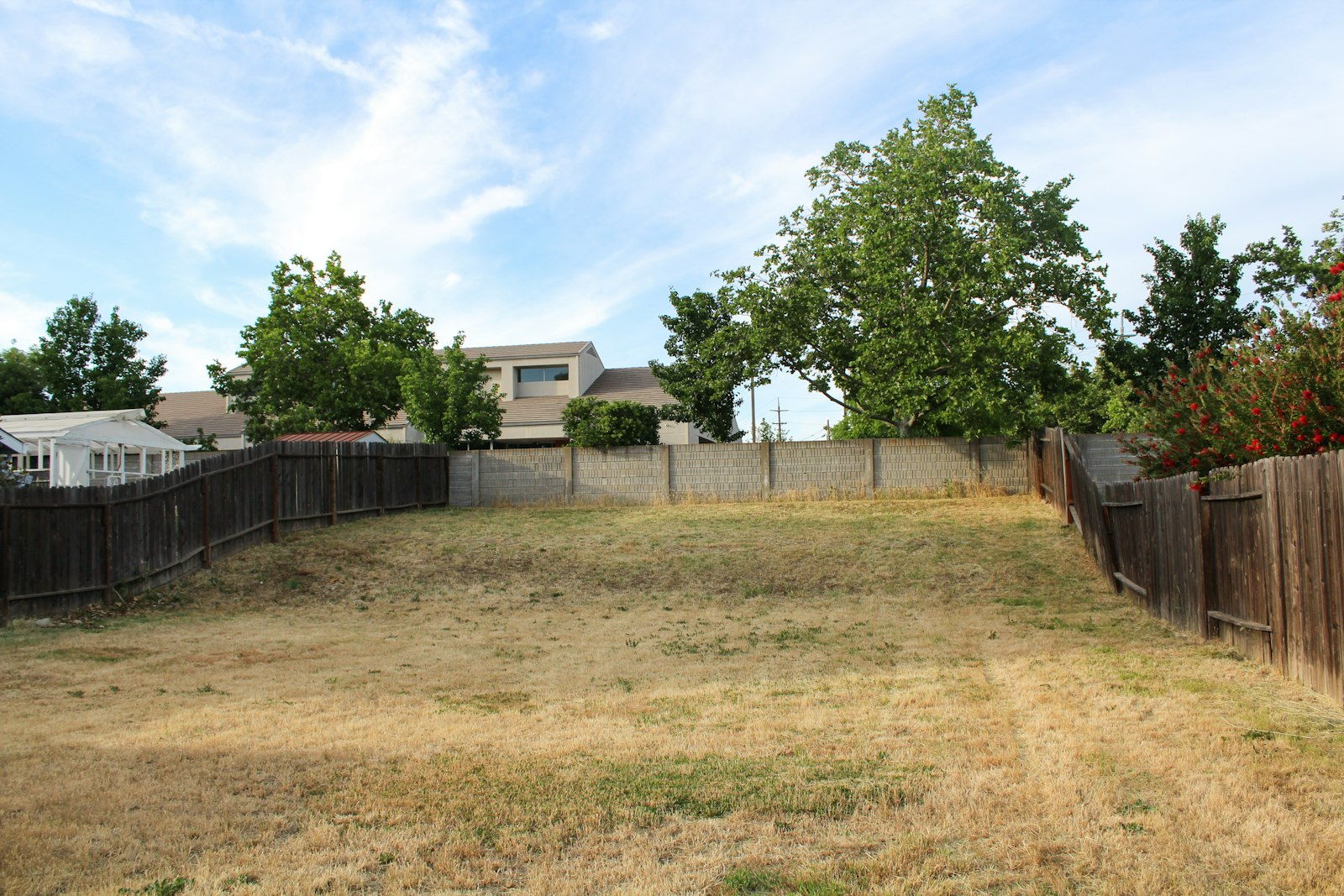 Bare dirt backyard before landscaping, enclosed by a wood fence