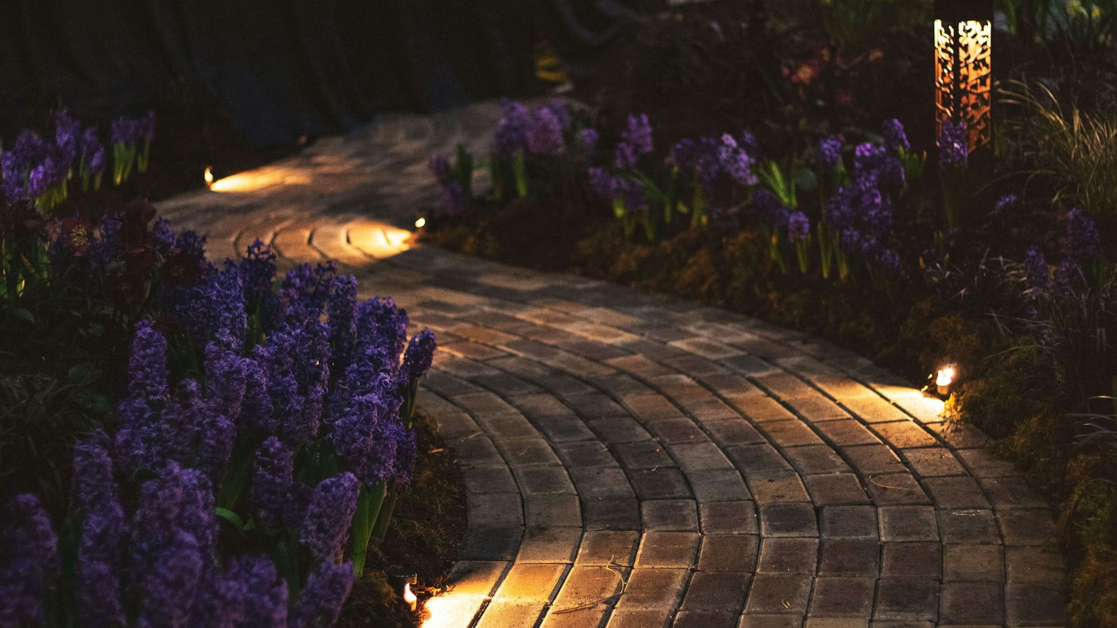 Landscape lighting along a paver walkway at dusk