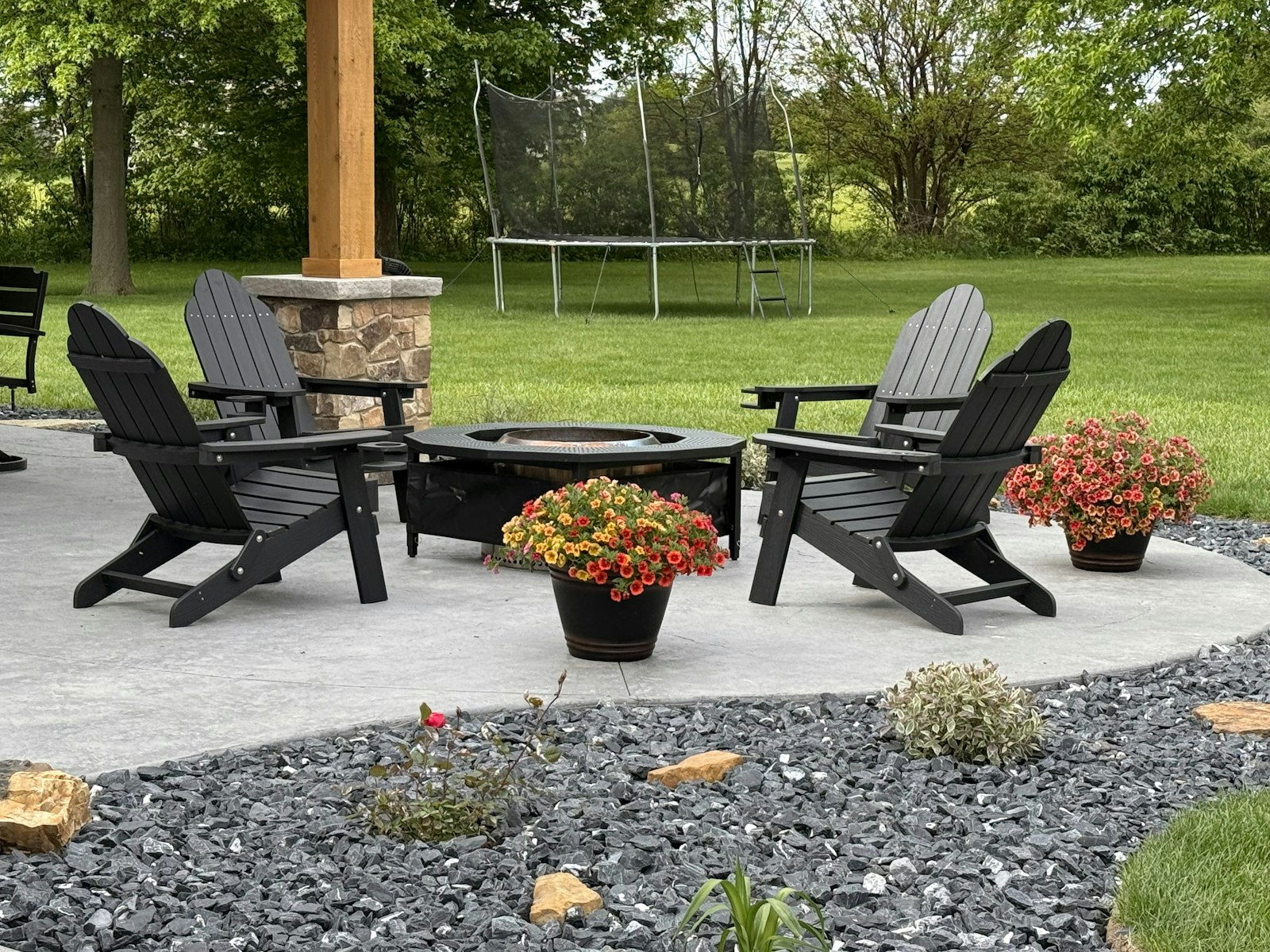 Backyard fire pit surrounded by chairs on a gravel and paver terrace