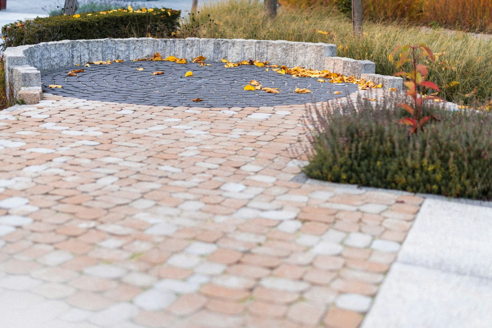 Paver driveway bordered by a low stacked stone retaining wall