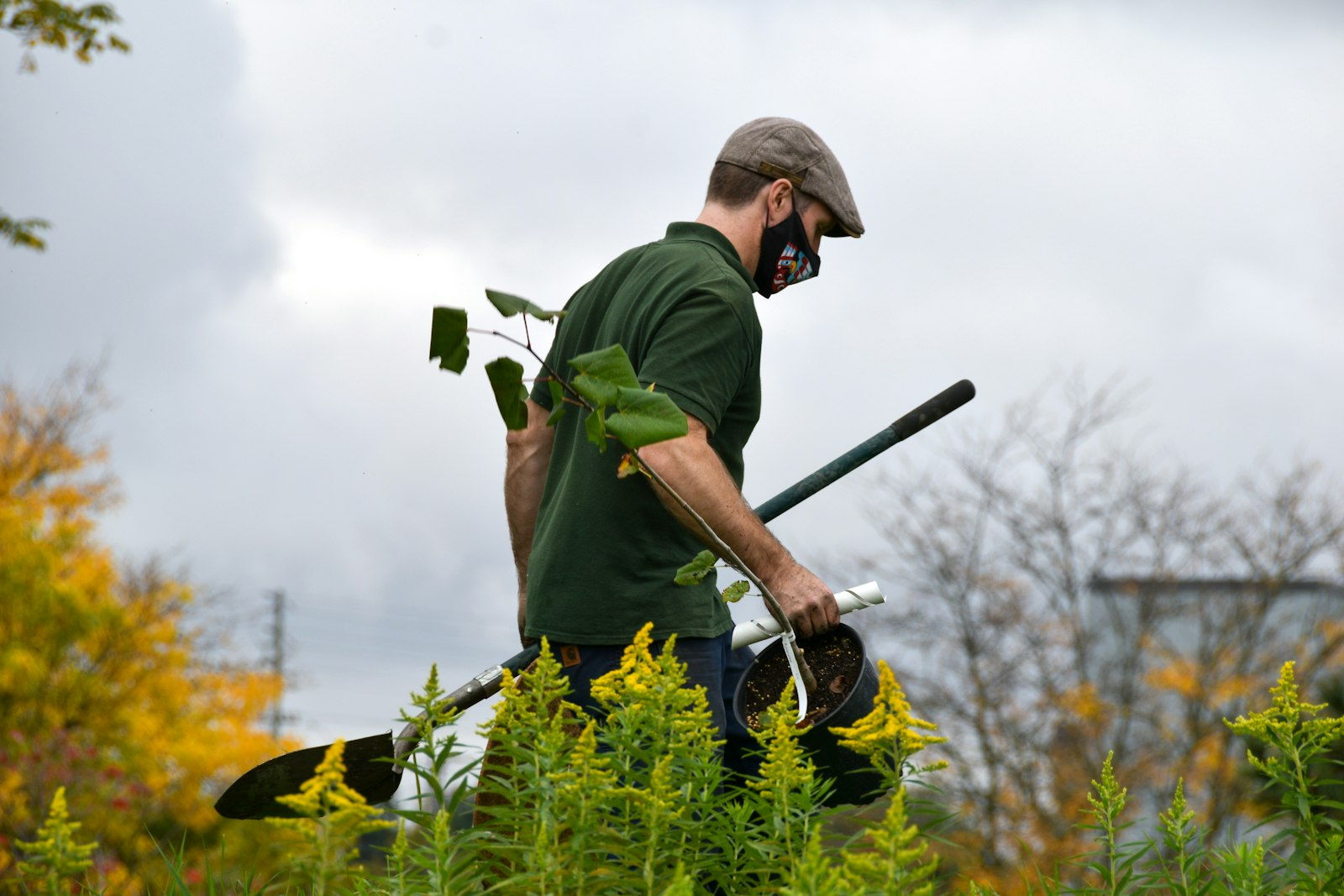 Landscape professional carrying tools across a residential yard